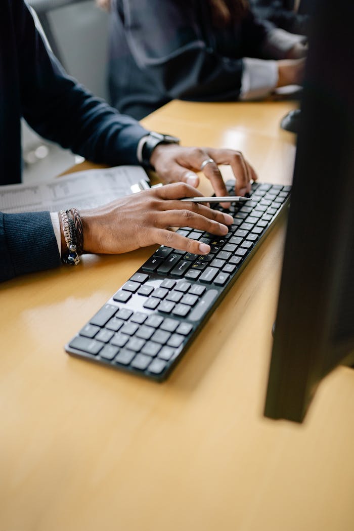 services-02 Close-up of hands typing on keyboard in an office setting, showcasing work professionalism.